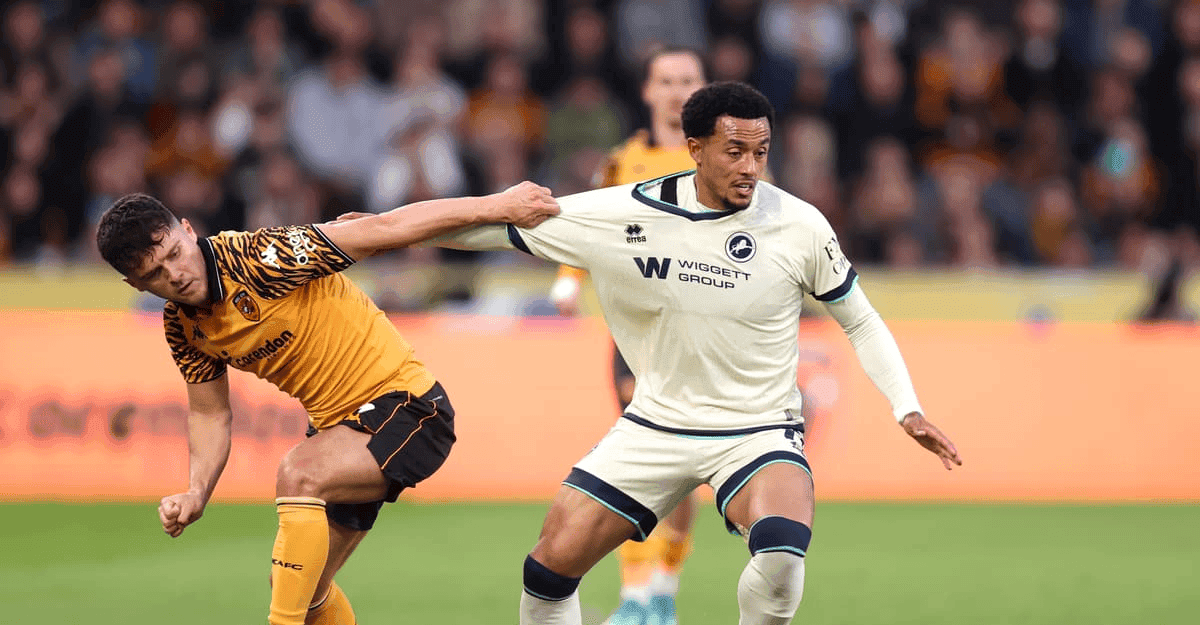 Femi Azeez in Millwall kit dribbling past a defender on the pitch